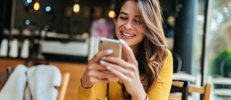 Mulher sorrindo olhando para o celular